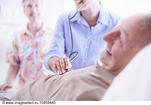 Doctor using stethoscope on senior man