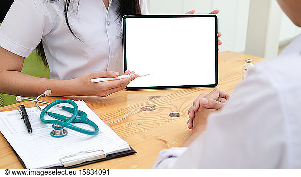 Doctor using tablet discussion something with patient.