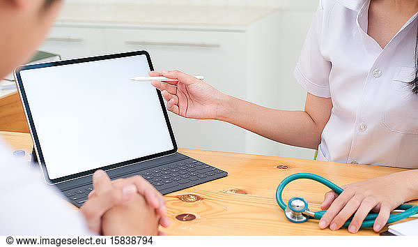 Doctor using tablet discussion something with patient.