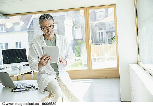 Doctor using tablet PC sitting in clinic