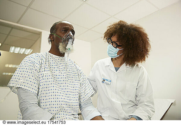 Doctor with protective face mask motivating patient in medical room