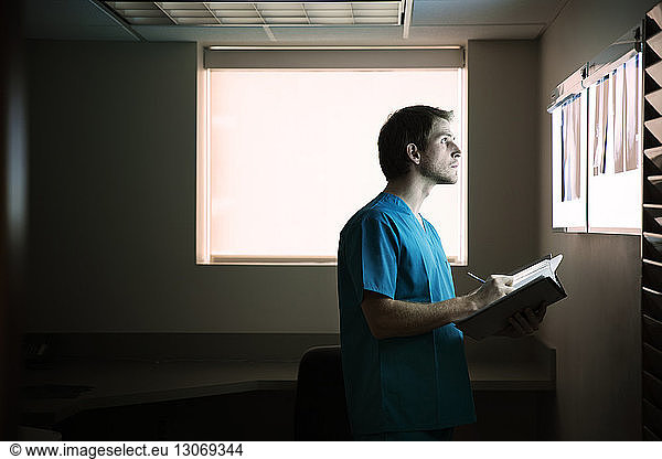 Doctor writing report while analyzing x-ray