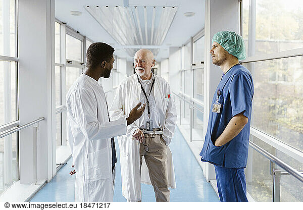 Doctors and physician discussing while standing in corridor at hospital