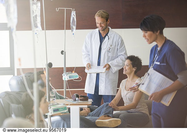 Doctors attending patients receiving intravenous infusion in hospital