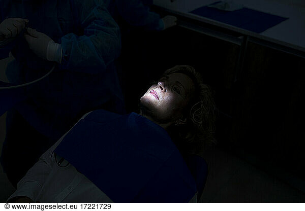 Doctors by patient in dark dental clinic