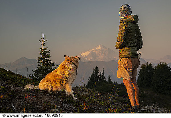 Dog and Male Hiker watching the light fade on glacier peak