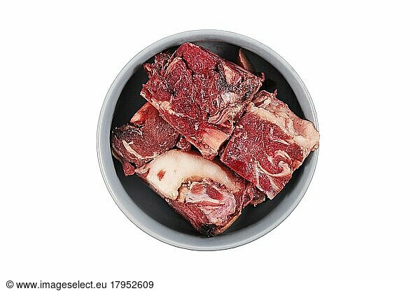 Dog bowl with big red chunks of meat with fat used for raw biologically appropriate feeding on white background