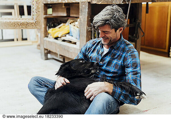Dog lying on man's lap in workshop