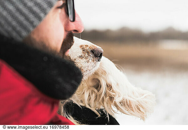 Dog's nose next to a male person's face outdoors.