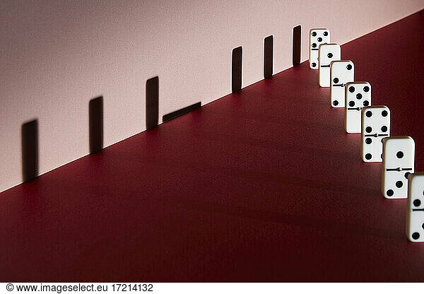 Dominosteine und Schatten soziale Distanzierung auf rotem Hintergrund