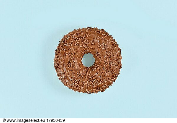 Donut glazed with chocolate with brown sprinkles on light blue background