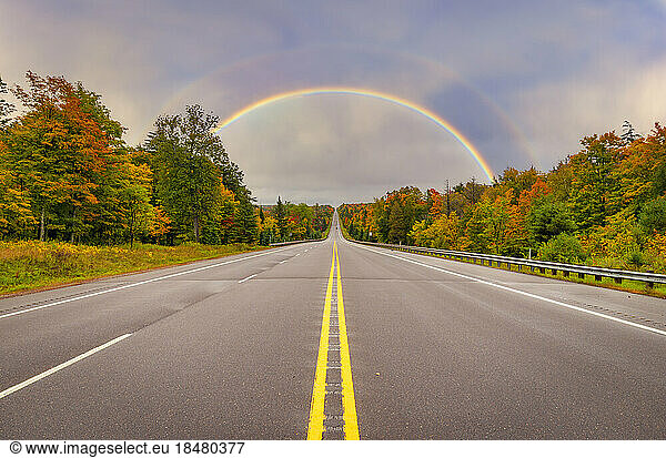 Double rainbow over highway at sunset
