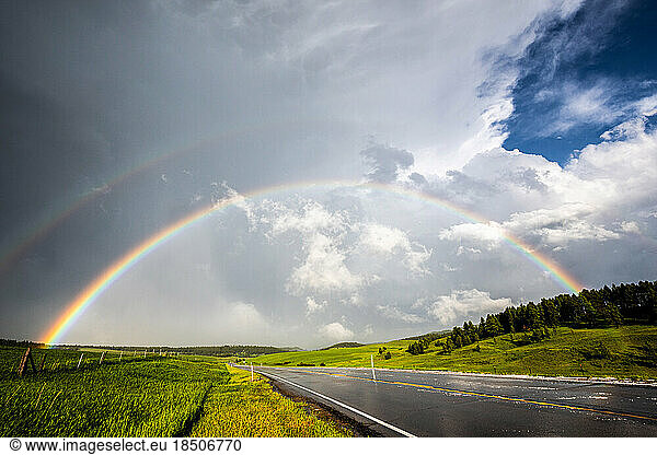 Double rainbow over road and green fields  cloudy sky