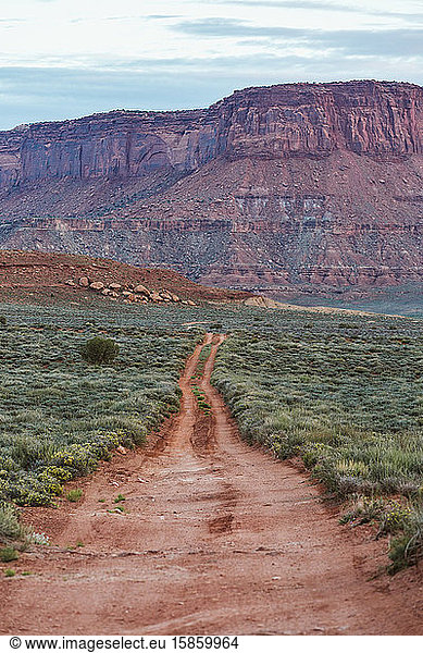 double track dirt road in the desert beneath red rock buttes of utah