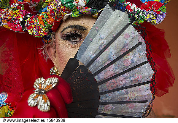 Drag Queen hiding face with oriental hand fan