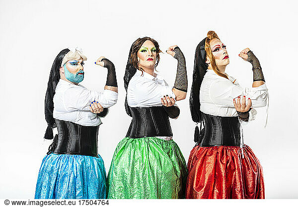 Drag queens in fishnet gloves flexing muscles by white background