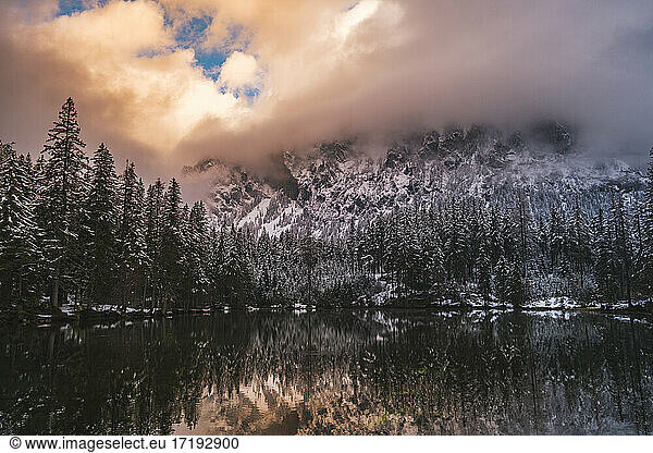 Dramatic landscape of lake in forest near mountains durring winter.