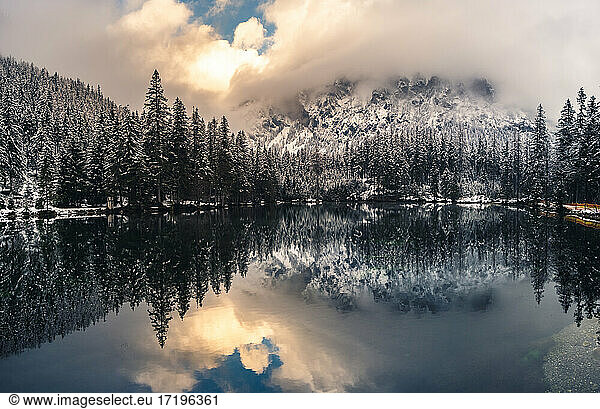 Dramatic landscape of lake in forest near mountains durring winter.
