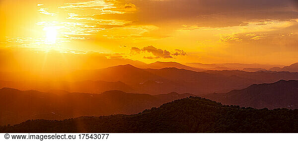 Dramatic orange sky over silhouette mountains in Montes de Malaga Natural Park at sunset  Andalucia  Spain  Europe