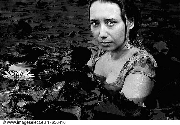 dramatic portrait of a girl in a lake with lotuses