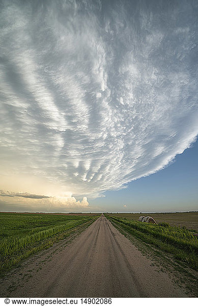 Dramatischer Himmel über einer unbefestigten Straße und einer Landschaft  gesehen während einer Sturmjagd im Mittleren Westen der Vereinigten Staaten; Kansas  Vereinigte Staaten von Amerika