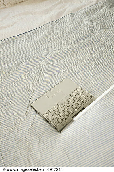 Draufsicht auf einen geöffneten Laptop auf dem Bett.