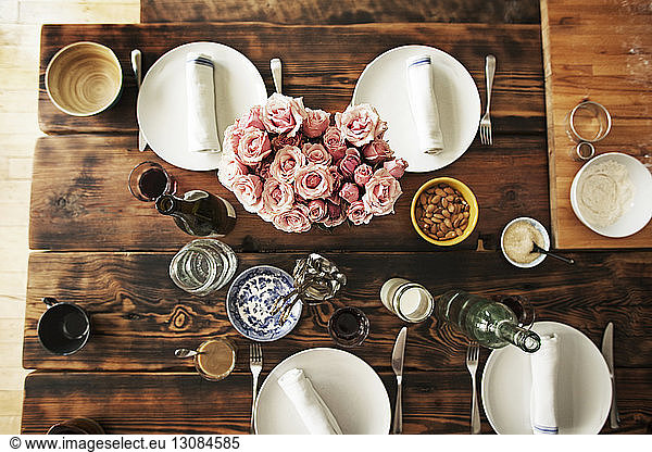 Draufsicht auf Essgeschirr und Rosen auf Holztisch