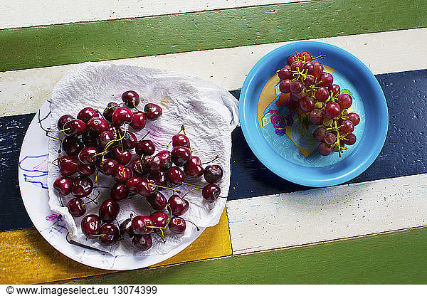 Draufsicht auf Kirschen und Trauben in Tellern auf dem Tisch