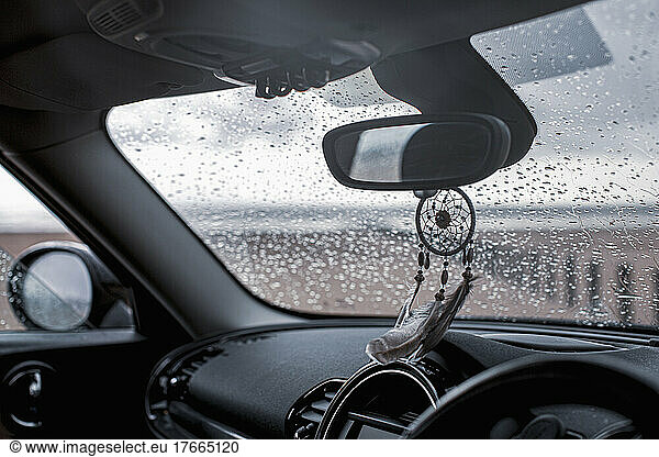 Dream catcher hanging from rear view mirror in car on wet beach
