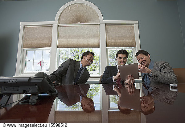 Drei Führungskräfte aus der Wirtschaft benutzen ein elektronisches Pad in einem Sitzungssaal
