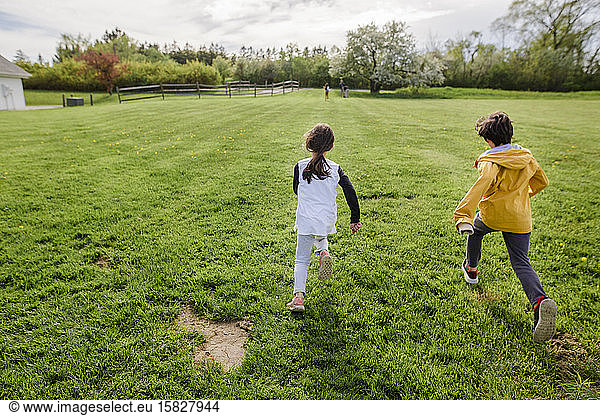 Drei Kinder rennen im Frühling durch ein Feld  eines weit voraus