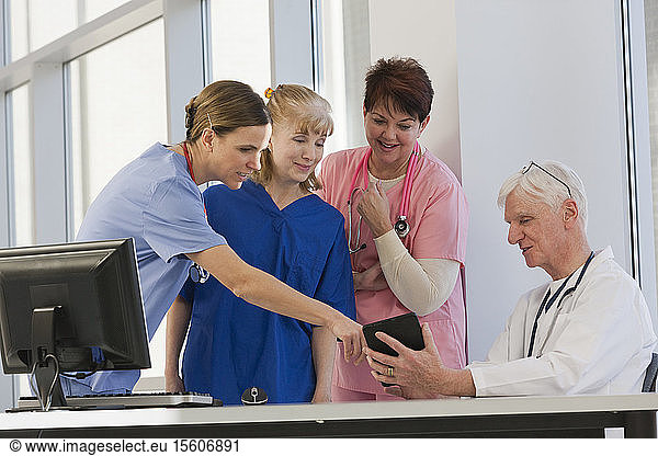 Drei Krankenschwestern besprechen Informationen vom Tablet mit dem Arzt