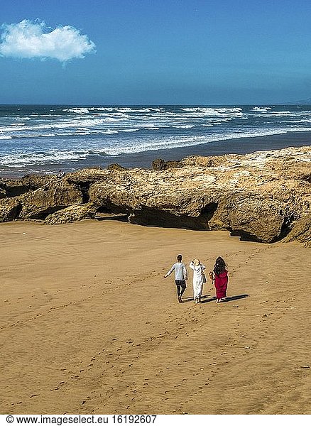 Drei Personen  die an einem Strand spazieren gehen  Essaouira  Marokko.