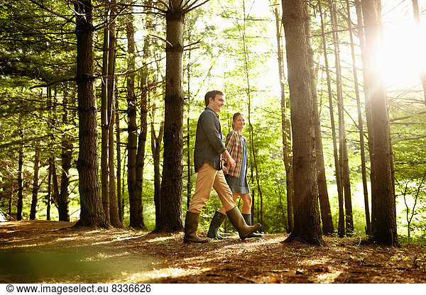 Drei Personen  eine Familie  die am späten Nachmittag im Wald spazieren geht.