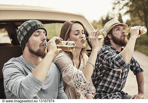 Drei Personen trinken gemeinsam Flaschenbier