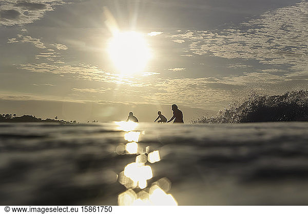 Drei Surfer bei Sonnenuntergang