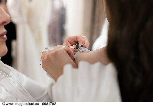 Dressmaker and female customer fitting and adjusting dress