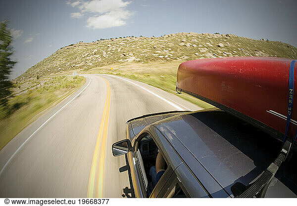 Driving along Horsetooth Reservoir with a canoe on top of the car near Fort Collins  Colorado.