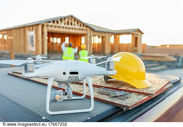 Drohnen-Quadcopter neben Schutzhelm auf Baustelle mit Arbeitern dahinter
