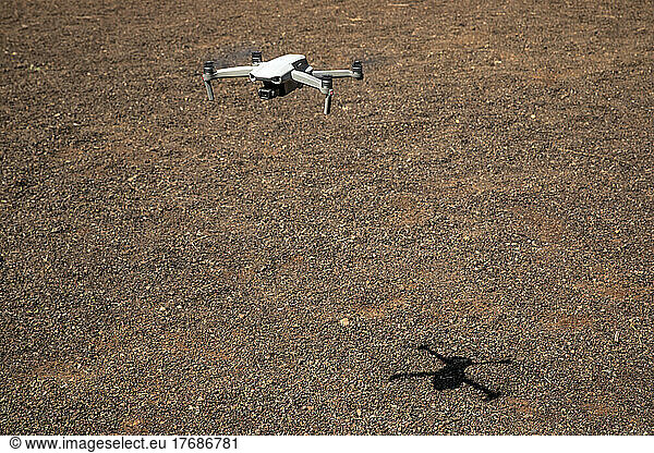 Drone flying over brown terrain full of pebbles