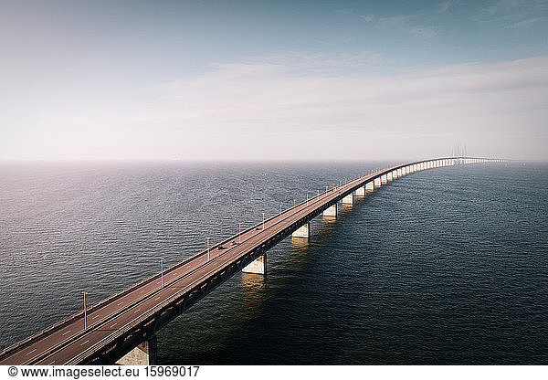 Drone view of bridge over sea against cloudy sky