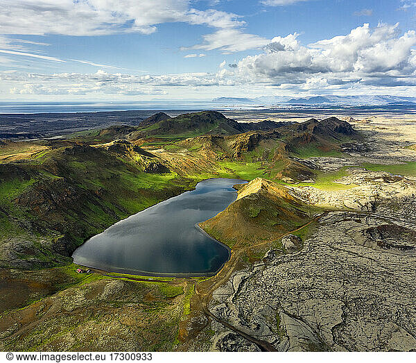 Drone view of calm lake in mountainous terrain on cloudy day in Iceland
