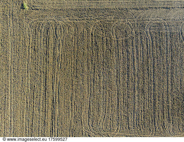 Drone view of plowed field covered in tire tracks