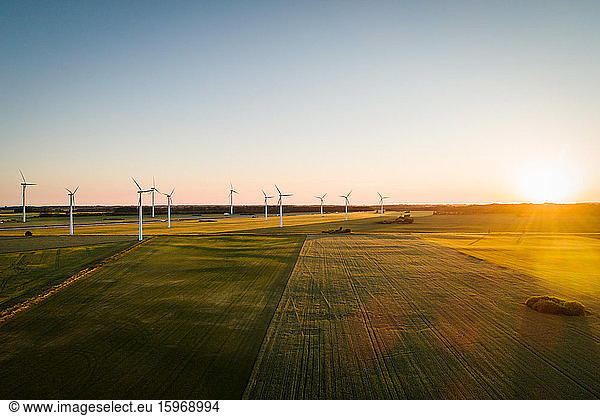 Drone view of windmills on grassy land against clear sky