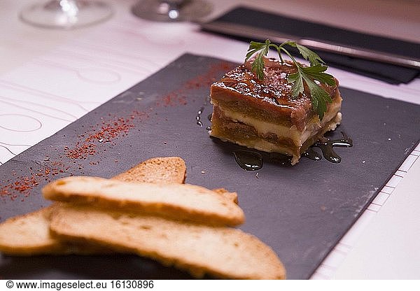 Duck foie pastry with quince jelly and toasts on plate in restaurant.