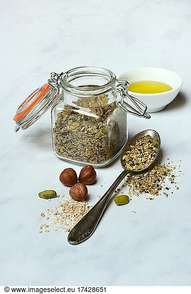 Dukkah  Arabic spice mix in glass container and spoon  nuts and small bowl with olive oil