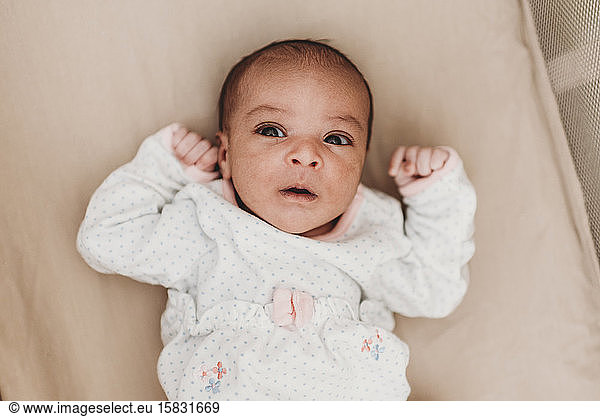 Dunkelhaariges  einmonatiges Baby mit weit geöffnetem Säuglingssaft in der Wiege liegend