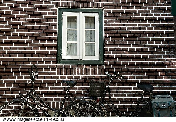 Dutch bikes leaning against red brick wall  brick  Frisian house  Frisian tradition  cycling  East Frisia  Dutch bike leaning against house wall  Aurich  Lower Saxony  Germany  Europe