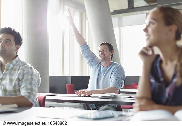 Eager man raising hand in adult education classroom