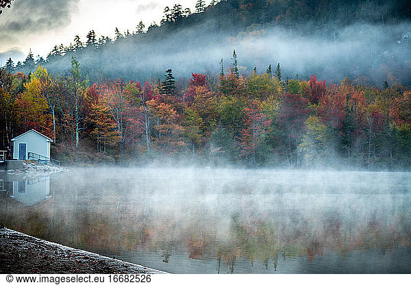 Early morning fog rising above calm lake in the White Mountains of NH.